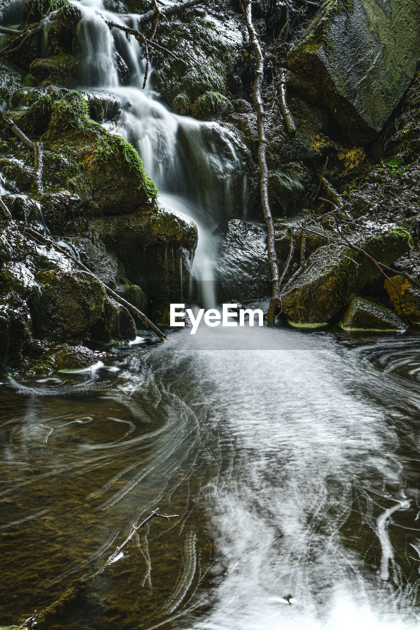 WATER FLOWING THROUGH ROCKS IN FOREST