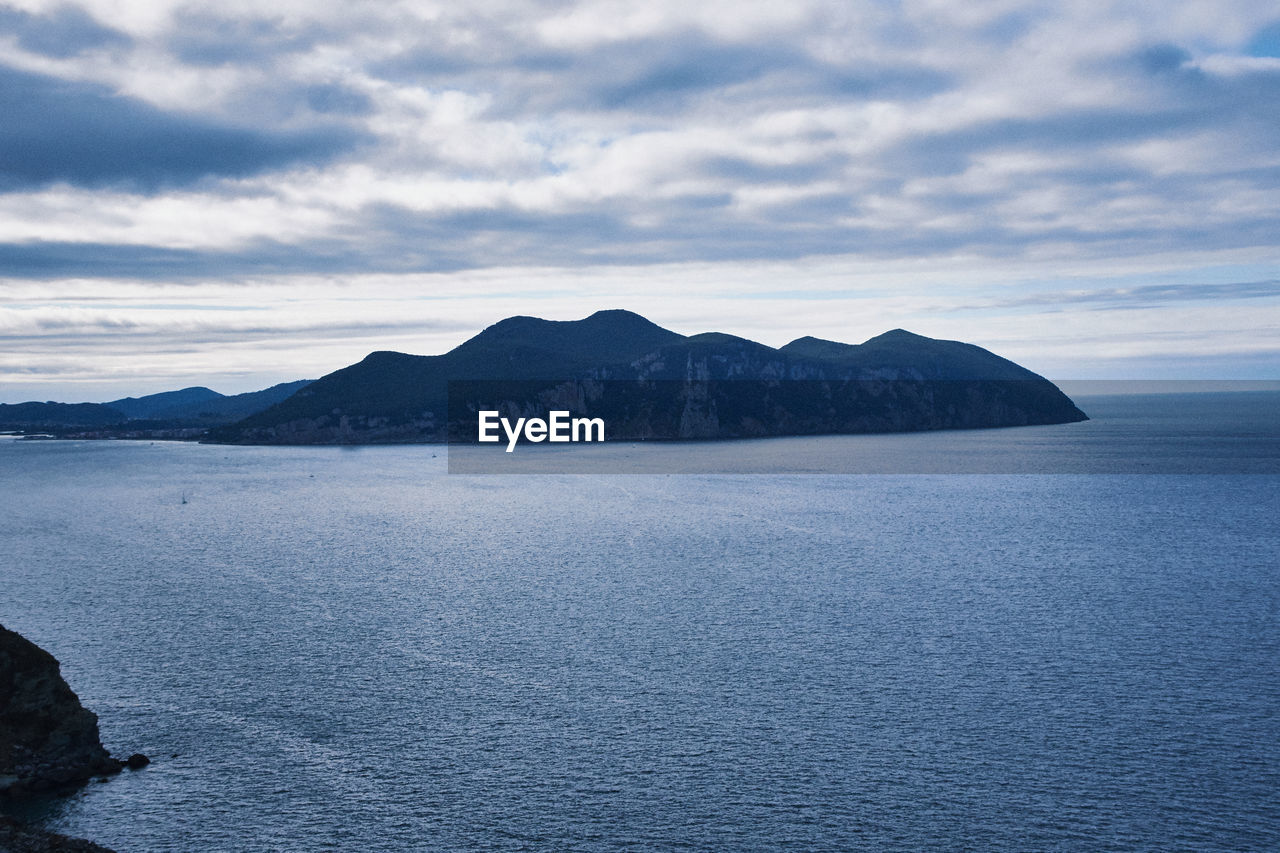 Scenic view of sea and mountains against sky