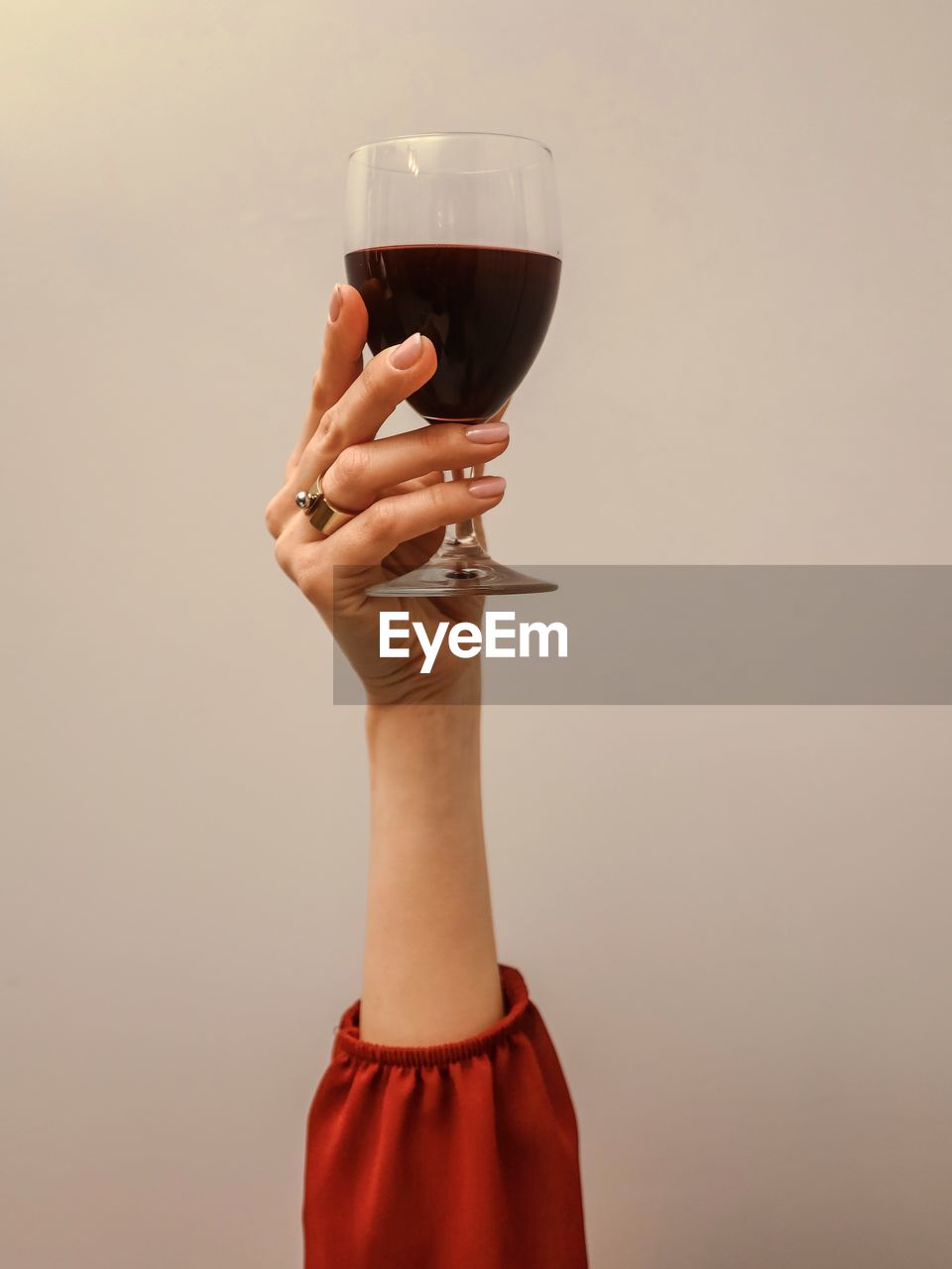 Cropped hand of woman holding wineglass against pink background