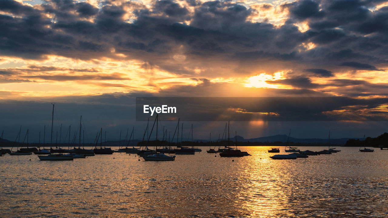 water, sky, cloud, nautical vessel, sea, transportation, sunset, beauty in nature, mode of transportation, nature, sailboat, scenics - nature, ship, harbor, tranquility, horizon, reflection, dramatic sky, dusk, travel, tranquil scene, sunlight, travel destinations, sailing, no people, sun, evening, idyllic, afterglow, environment, outdoors, beach, yacht, holiday, vacation, seascape, trip, mast, shore, pier, architecture, tourism, cloudscape, boat, vehicle, coast, moody sky, land, ocean, landscape, sailing ship, bay, moored, silhouette, city