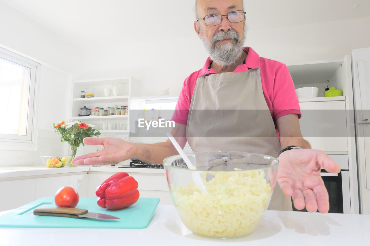 Midsection of senior man preparing food in kitchen