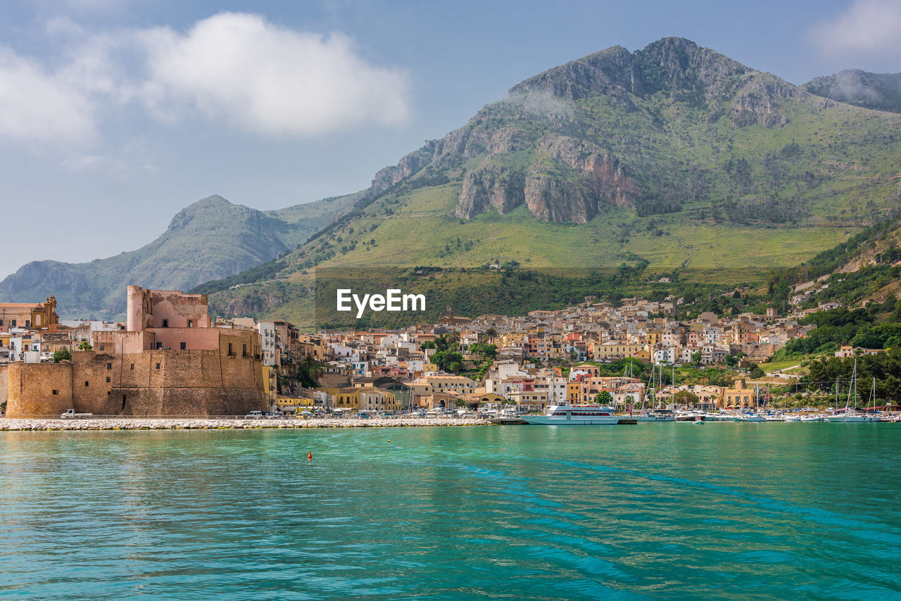 Scenic view of sea by buildings against sky