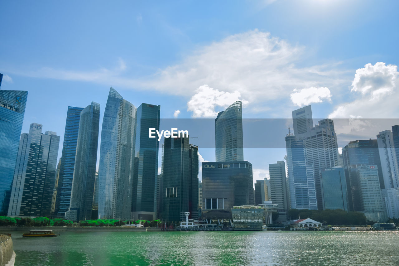 BUILDINGS BY RIVER AGAINST SKY