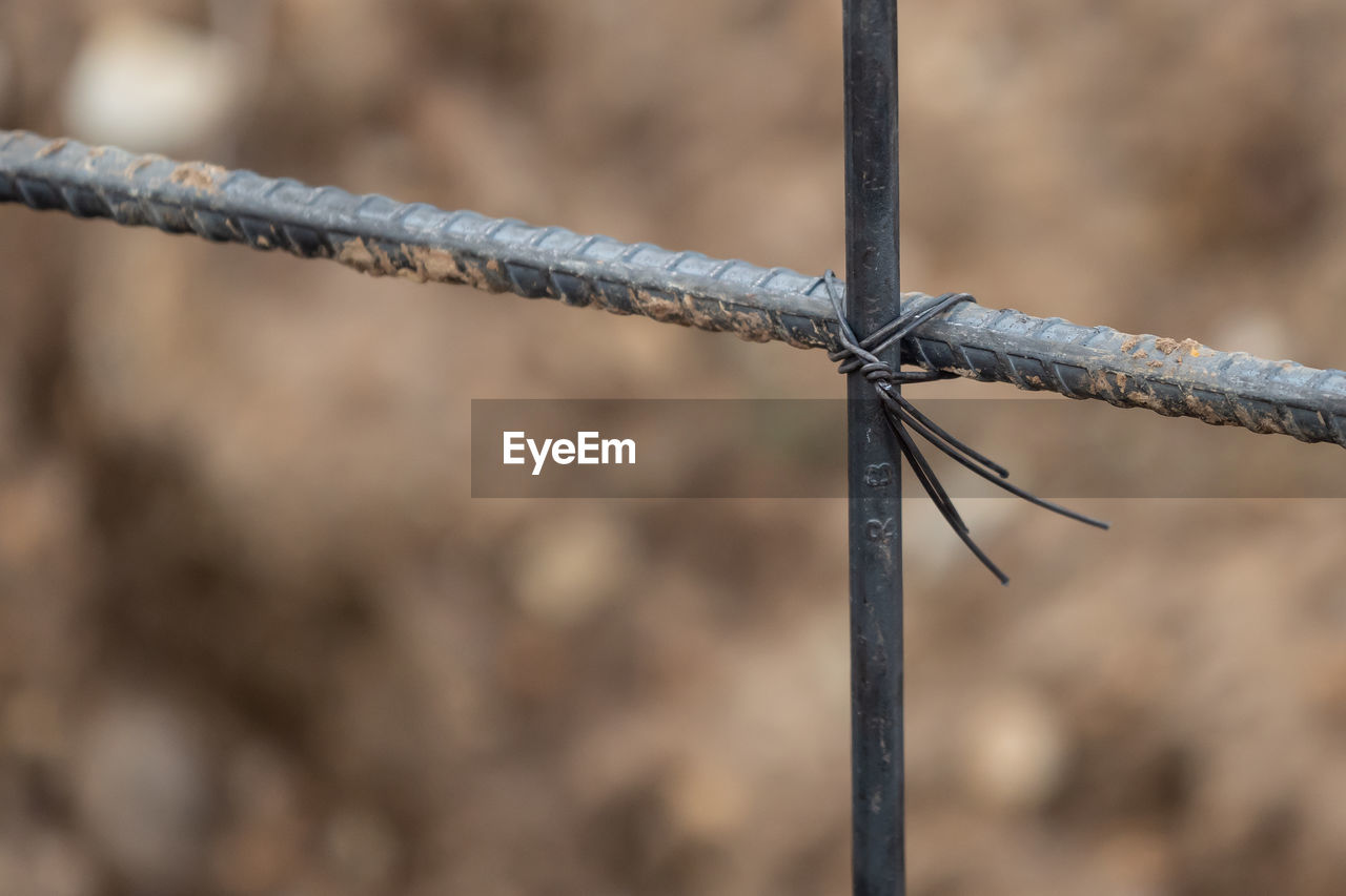 Close-up of barbed wire tied up to fence