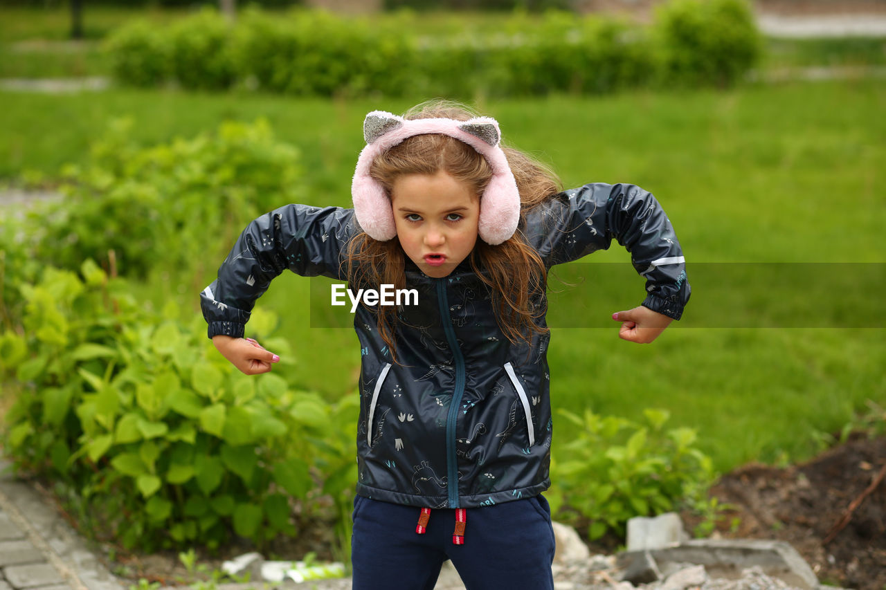childhood, child, one person, nature, front view, clothing, day, toddler, green, men, outdoors, plant, portrait, three quarter length, focus on foreground, person, lifestyles, innocence, emotion, standing, smiling, leisure activity, cute, sports, casual clothing, happiness, looking at camera, female, fun, blond hair