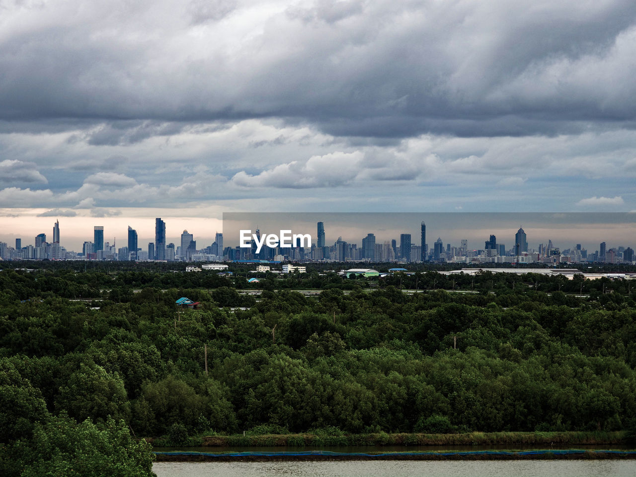 Bangkok city skyline as seen from the legume forest of suburban bang khun thian bangkok thailand