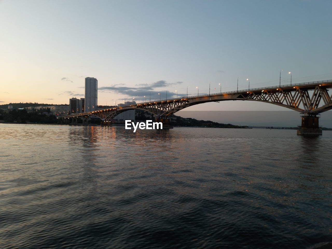 BRIDGE OVER RIVER IN CITY AT SUNSET