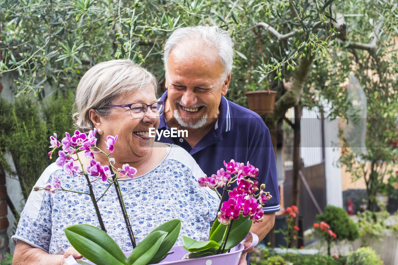 Smiling senior couple holding plants at back yard