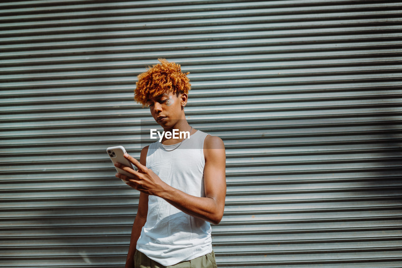 Young dark-skinned man posing at the street and taking selfie in the city background