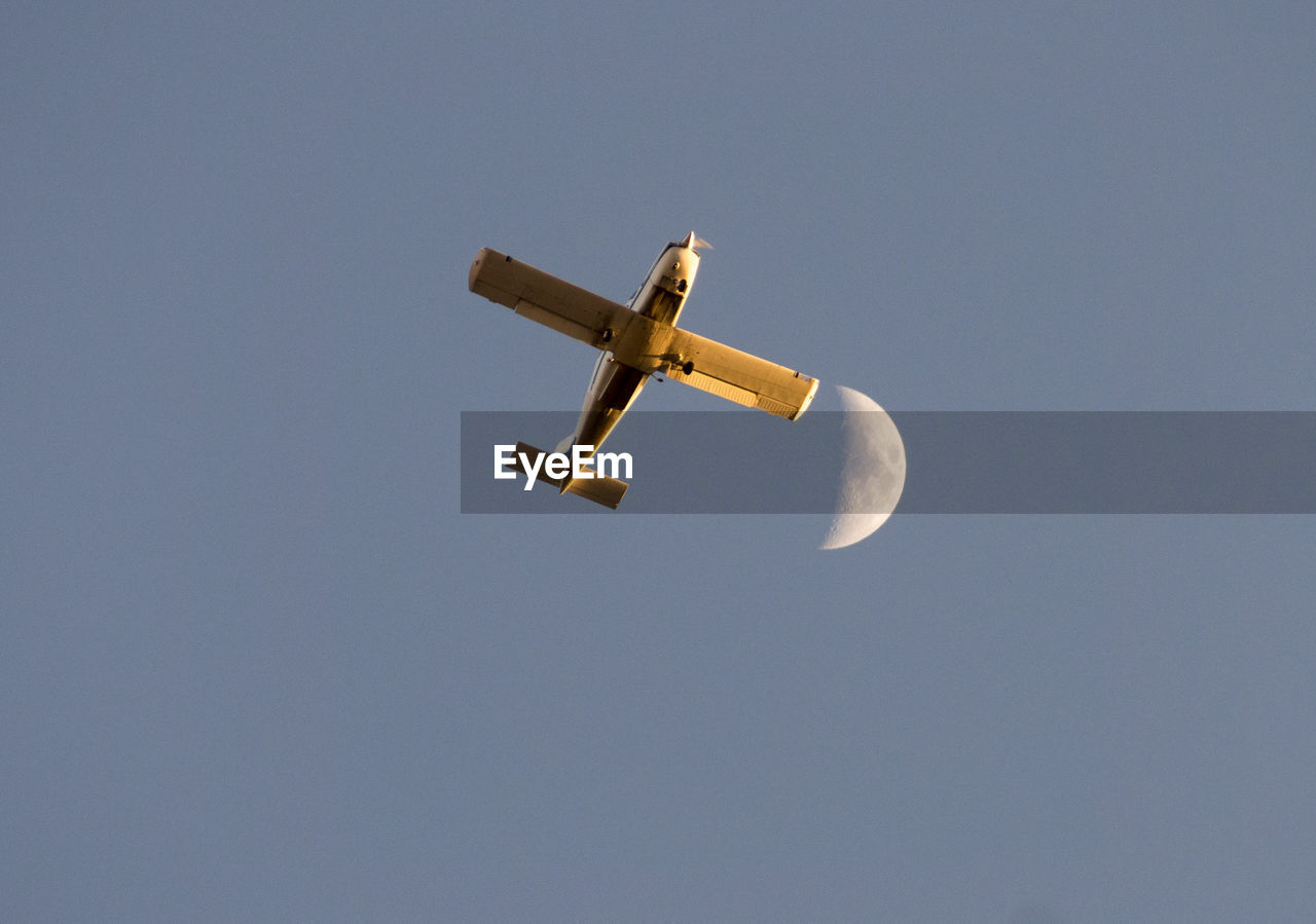 Low angle view of fighter plane and moon against blue sky