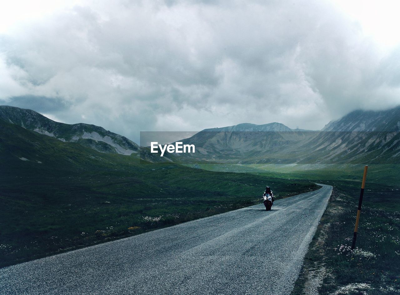 Rear view of people riding on mountain road