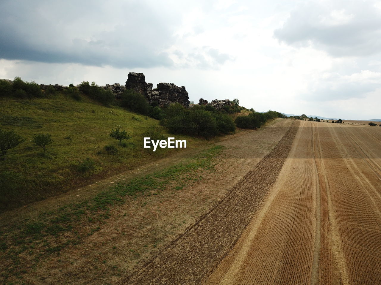 ROAD PASSING THROUGH AGRICULTURAL FIELD AGAINST SKY