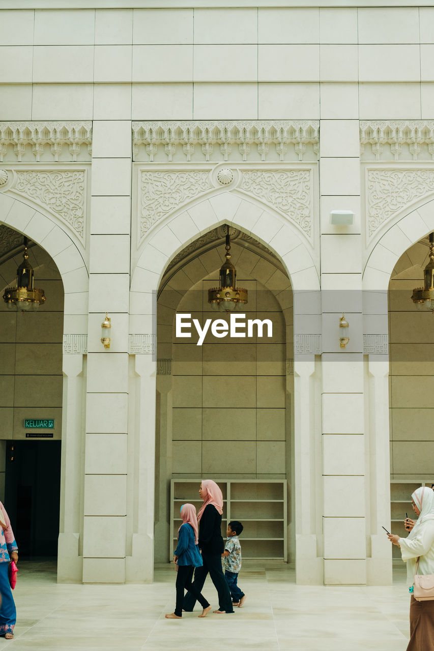 REAR VIEW OF PEOPLE WALKING ON BUILDING ENTRANCE