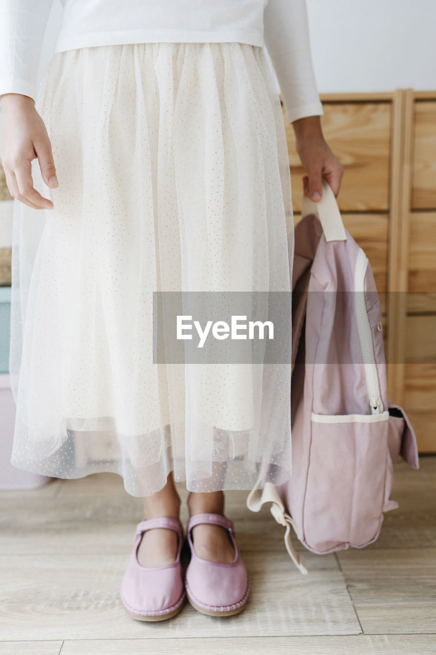 Girl holding pink backpack wearing matching shoes