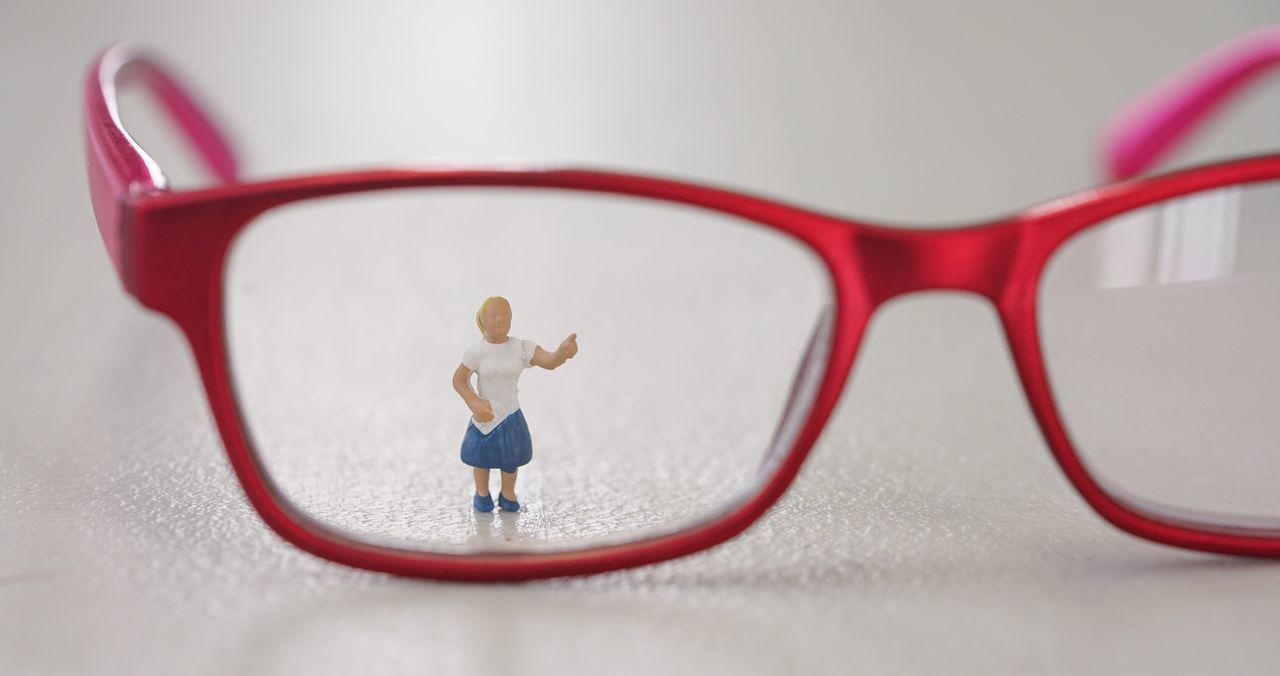 Close-up of female figurine seen through eyeglasses on table