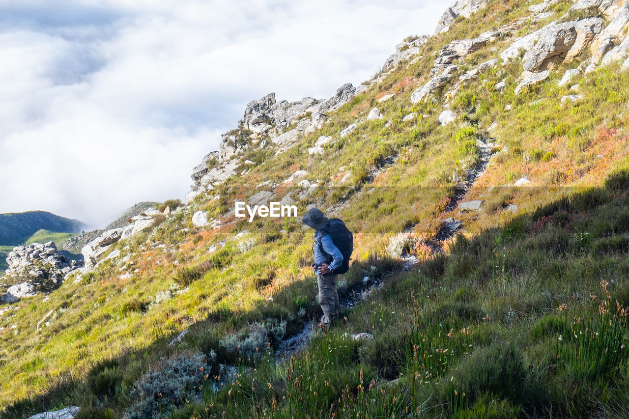 Hikers with backpack standing on a slope looking at mountain and cloud view 