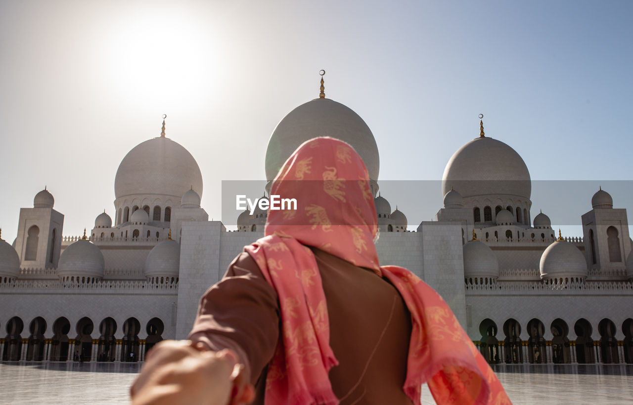 Cropped image of man holding woman hand at sheikh zayed mosque during sunny day