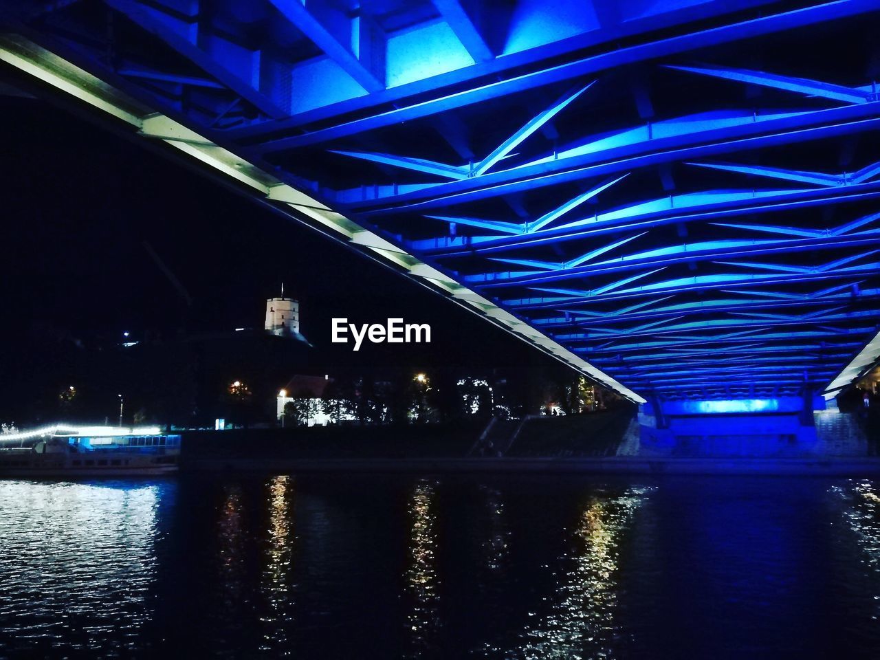 ILLUMINATED BRIDGE OVER RIVER IN CITY