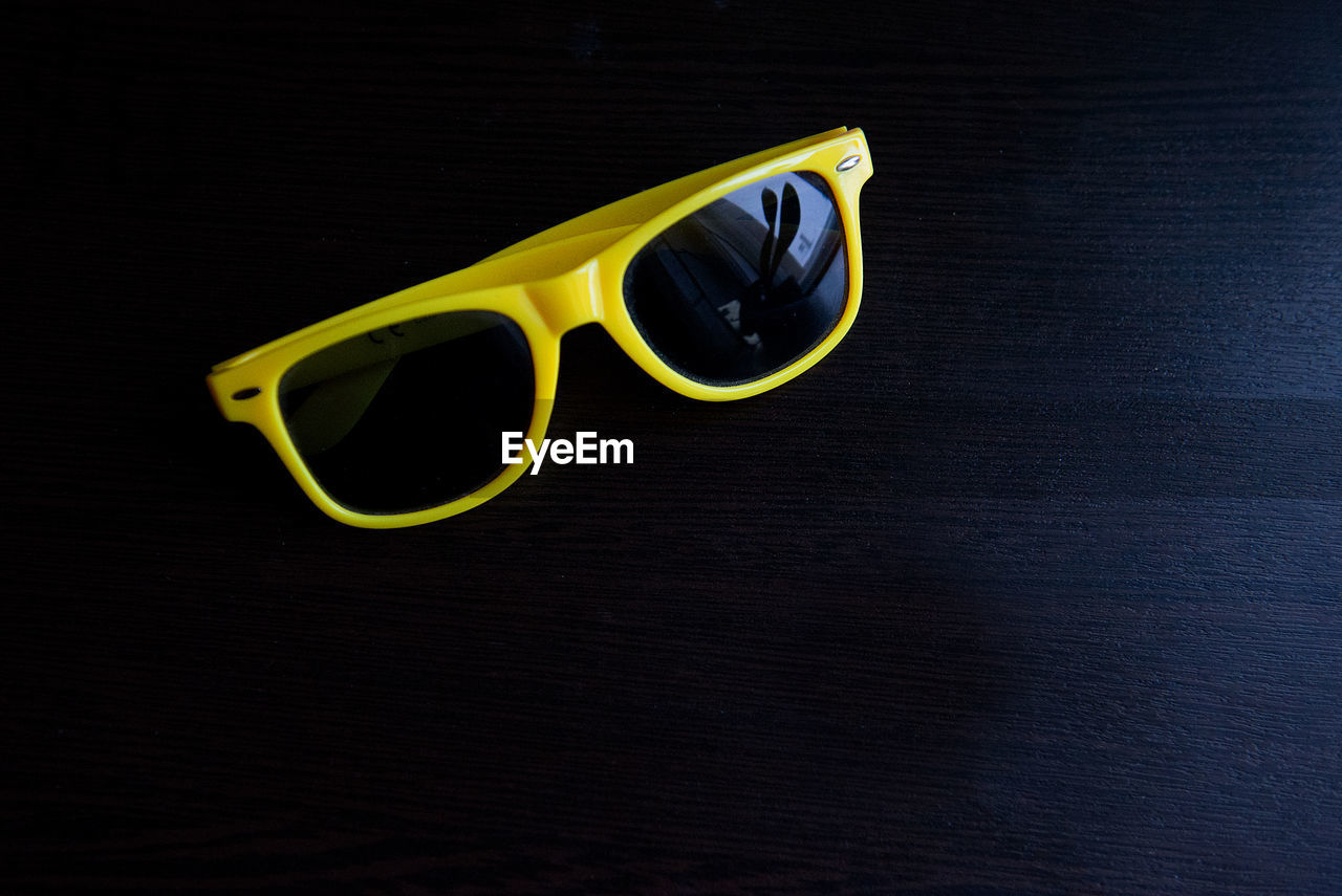Directly above shot of yellow sunglasses on wooden table