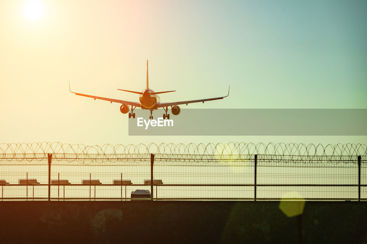 Low angle view of airplane flying against sky during sunset