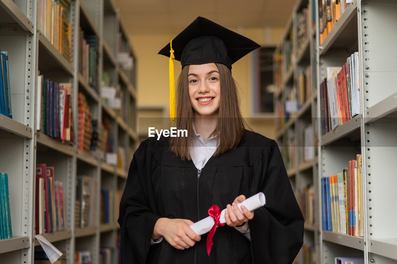 portrait of smiling woman wearing graduation in library