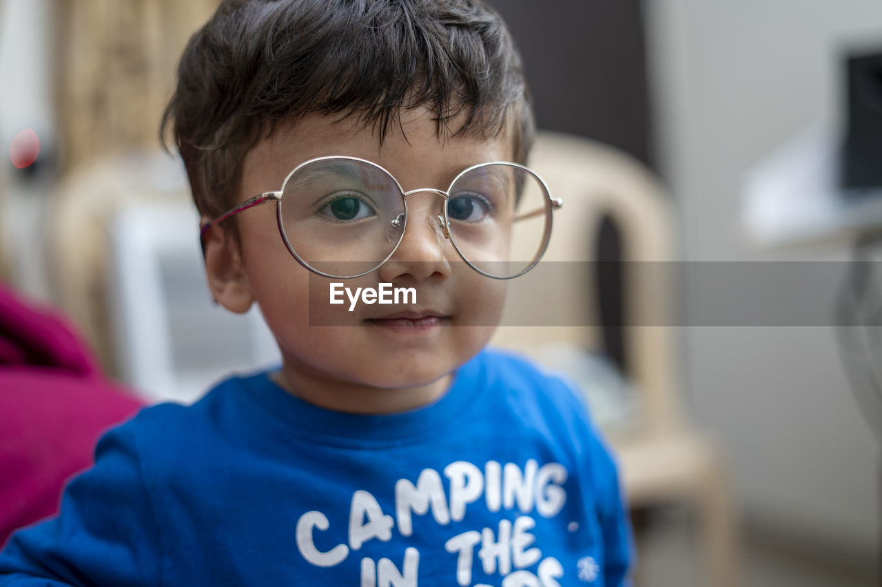 Close-up portrait of cute boy wearing eyeglasses at home