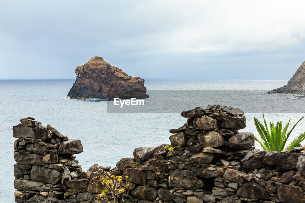 Rock formation by sea against sky