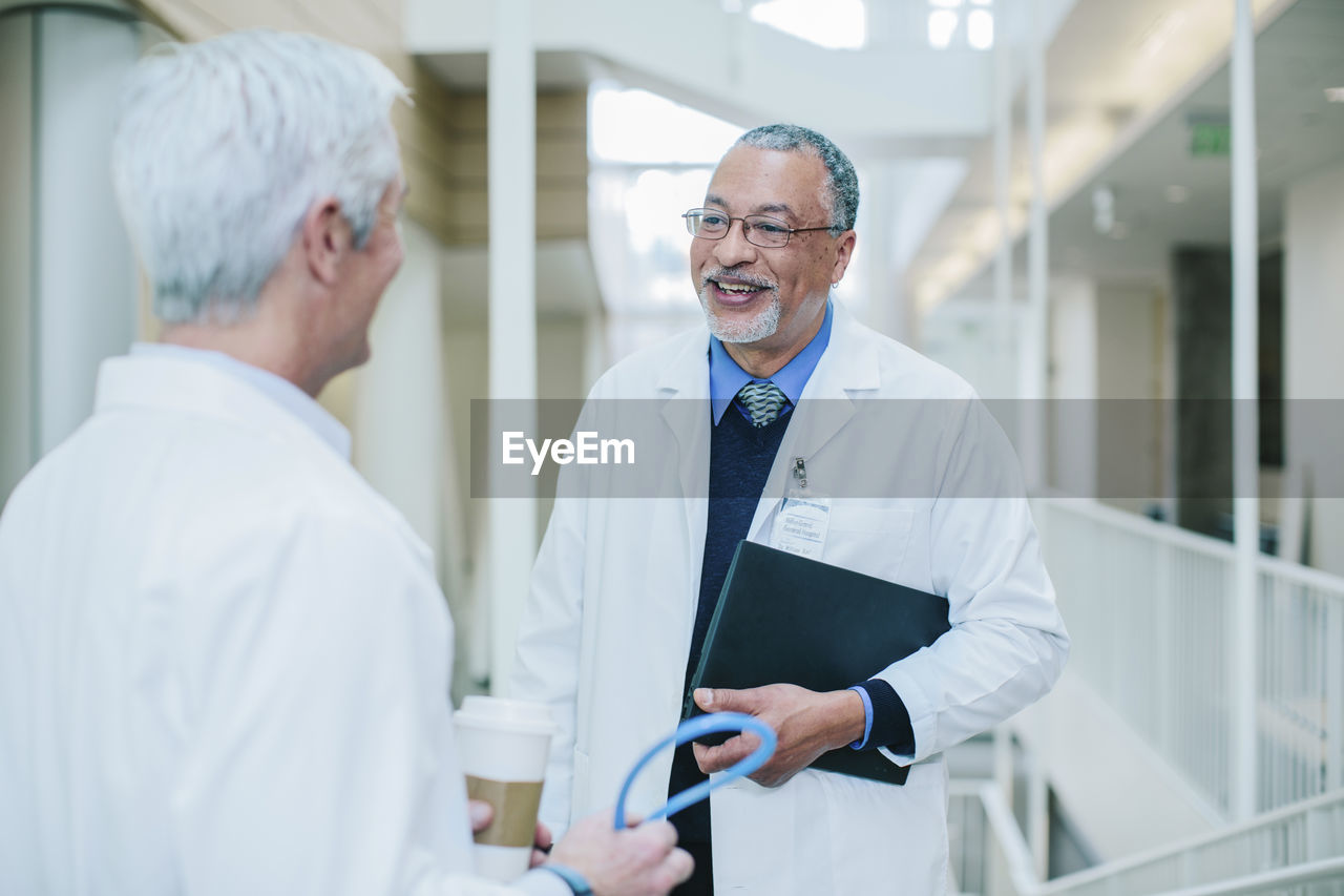 Male doctors talking while standing in hospital corridor