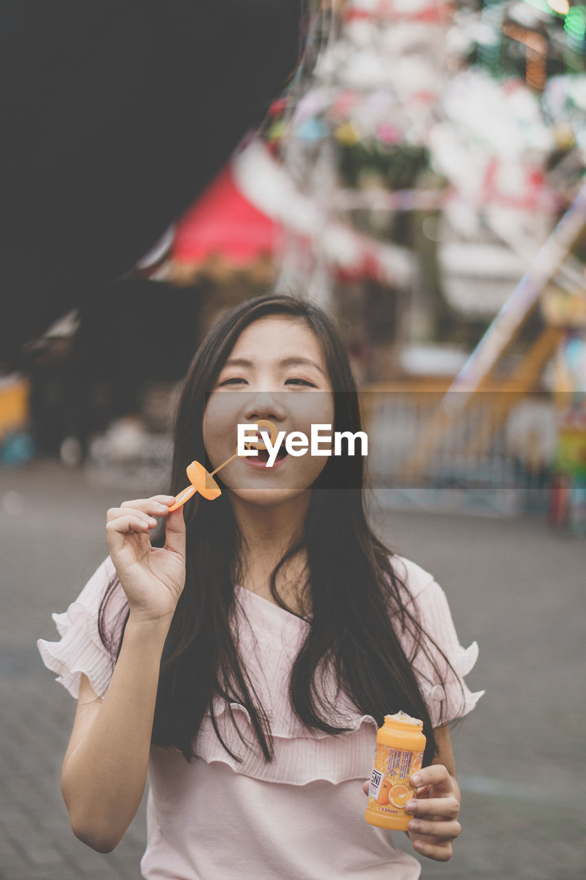 Young woman blowing bubble at amusement park