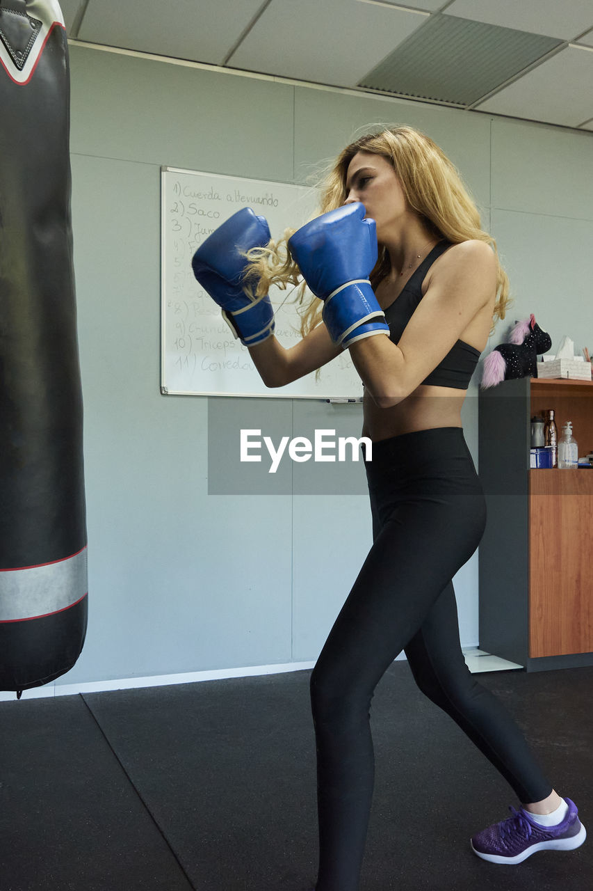 Side view of confident female boxer exercising in gym