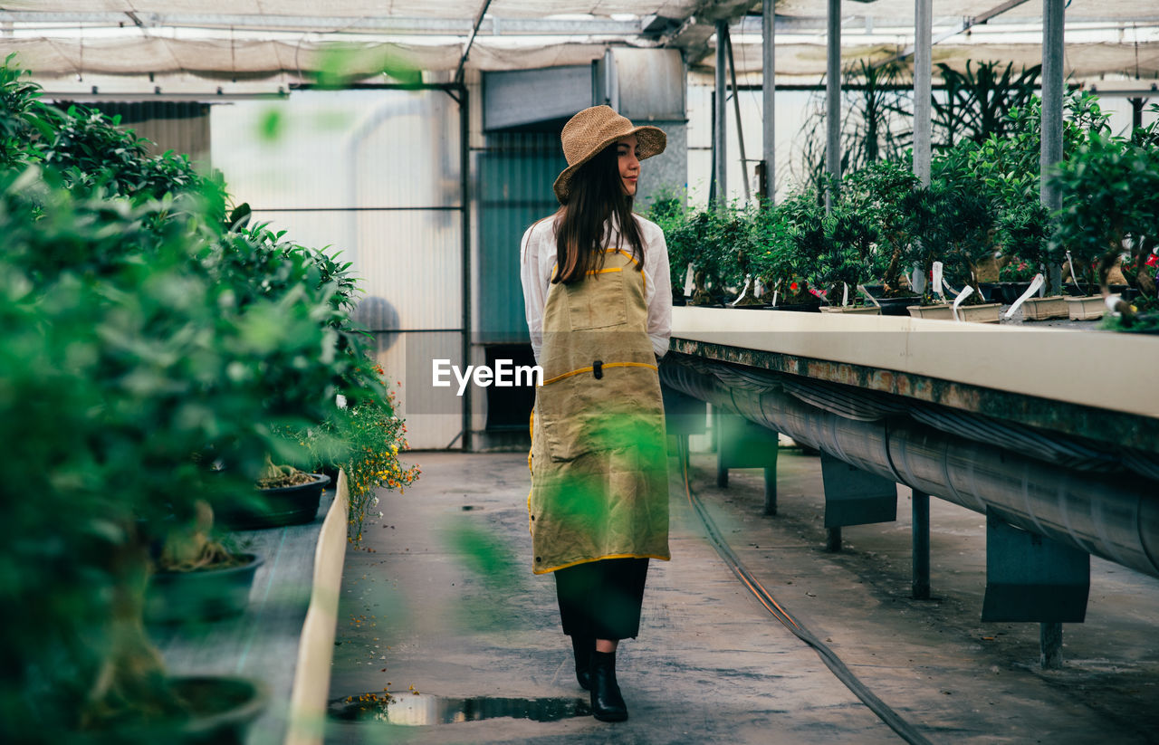 Full length of woman walking in greenhouse