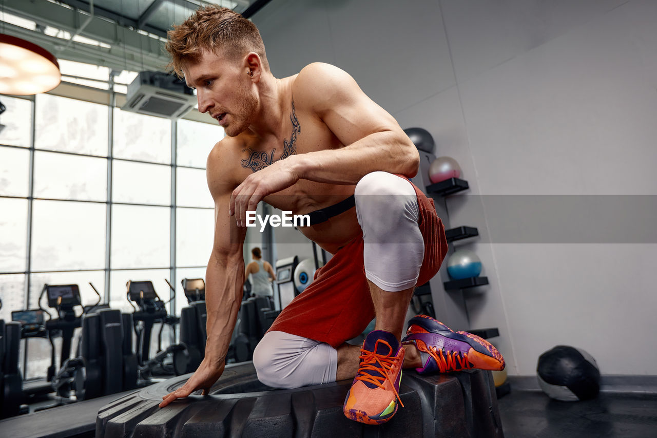 full length of young woman exercising at gym