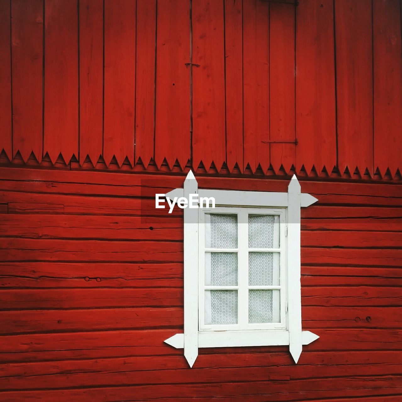 Window with white frame on red wooden wall