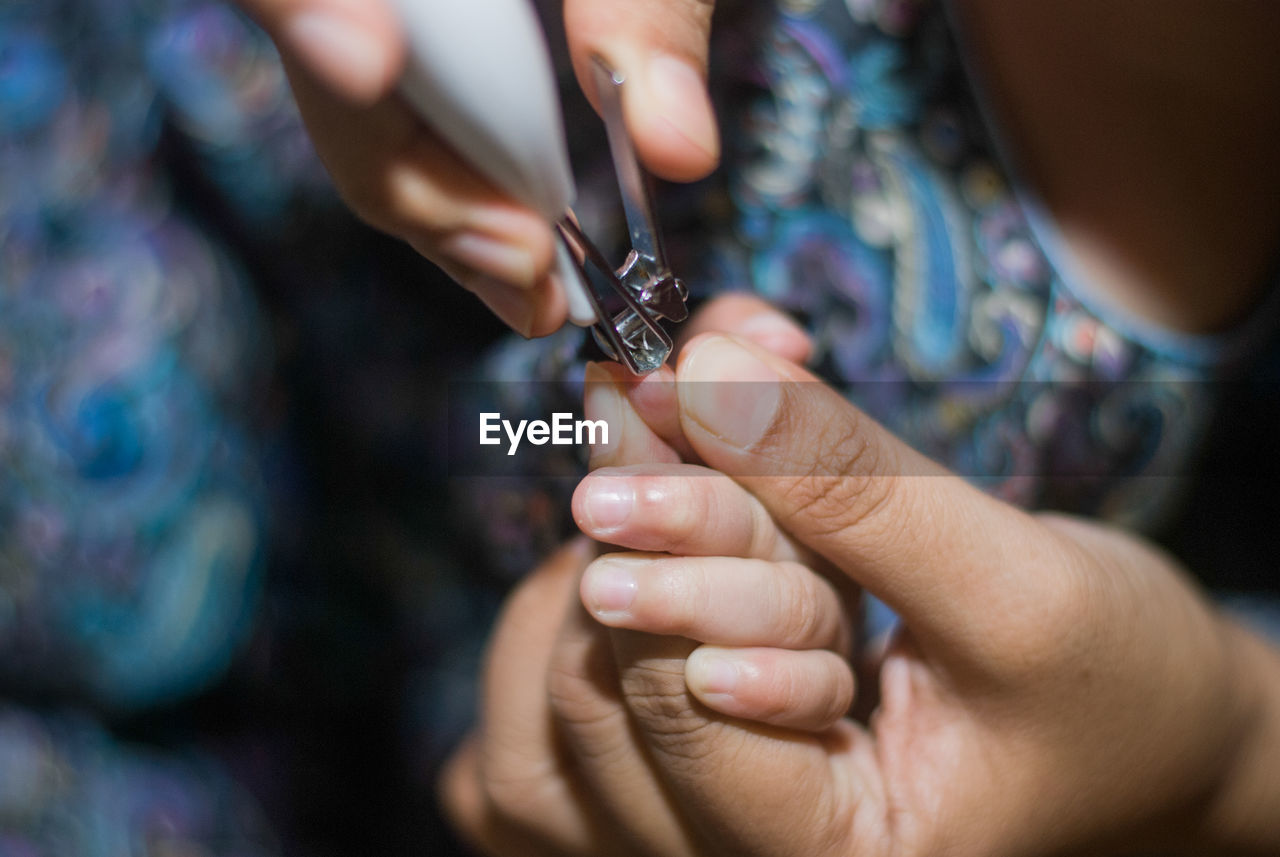 Cropped image of mother cutting fingernails of child