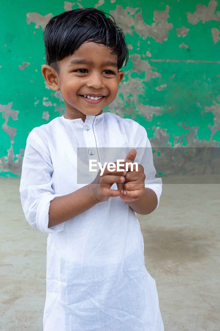 PORTRAIT OF CUTE BOY STANDING AGAINST WALL