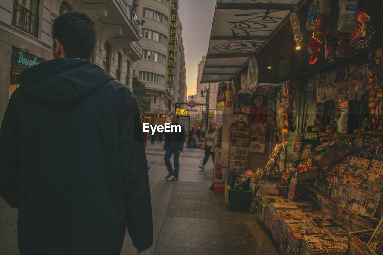 REAR VIEW OF PEOPLE WALKING ON STREET AT MARKET