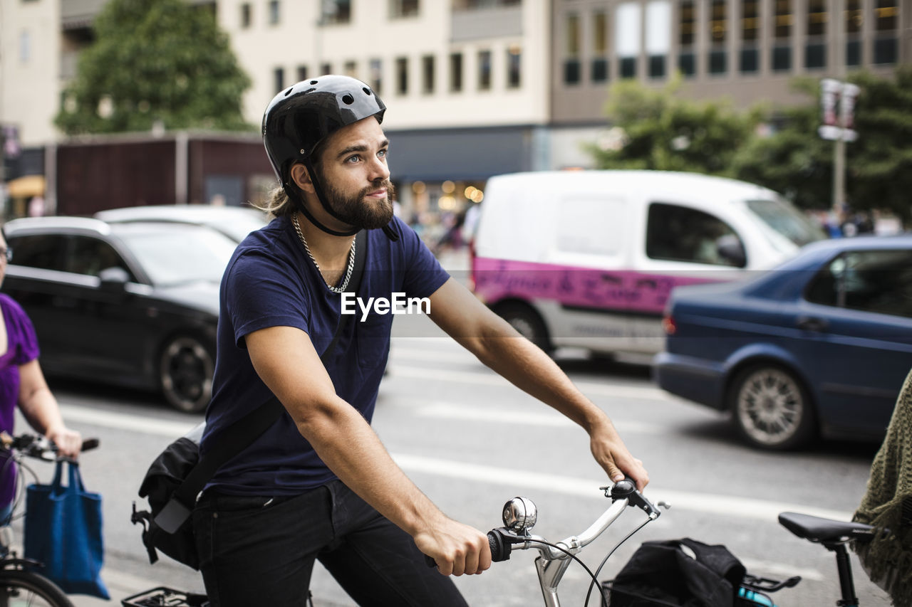 Thoughtful man riding bicycle in traffic on city street