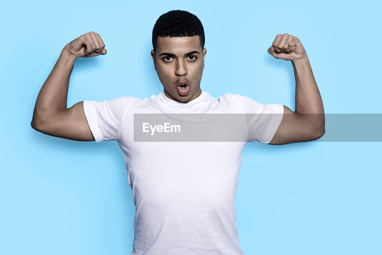 PORTRAIT OF YOUNG MAN STANDING AGAINST WHITE BACKGROUND