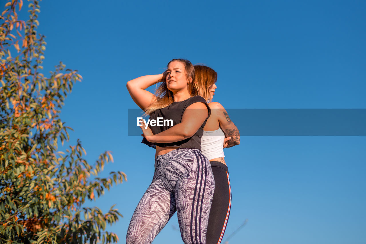 Low angle view of women in sports clothing against clear sky