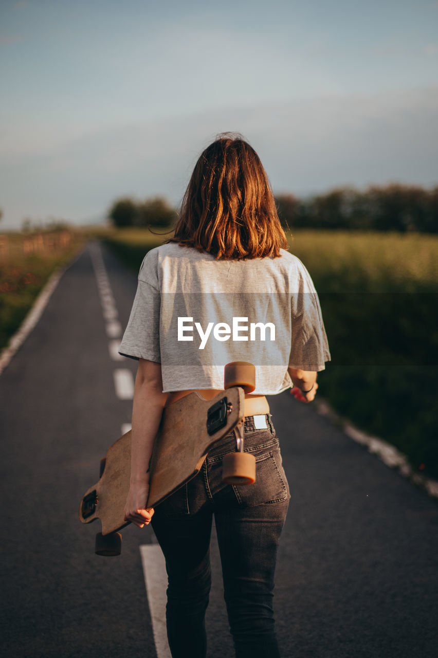 Rear view of woman standing on road