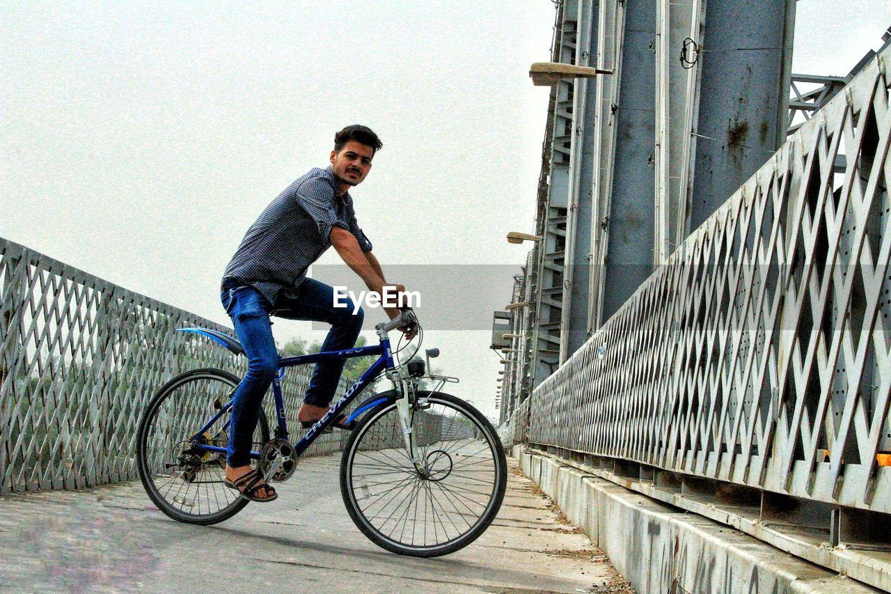 YOUNG MAN RIDING BICYCLE ON CITY