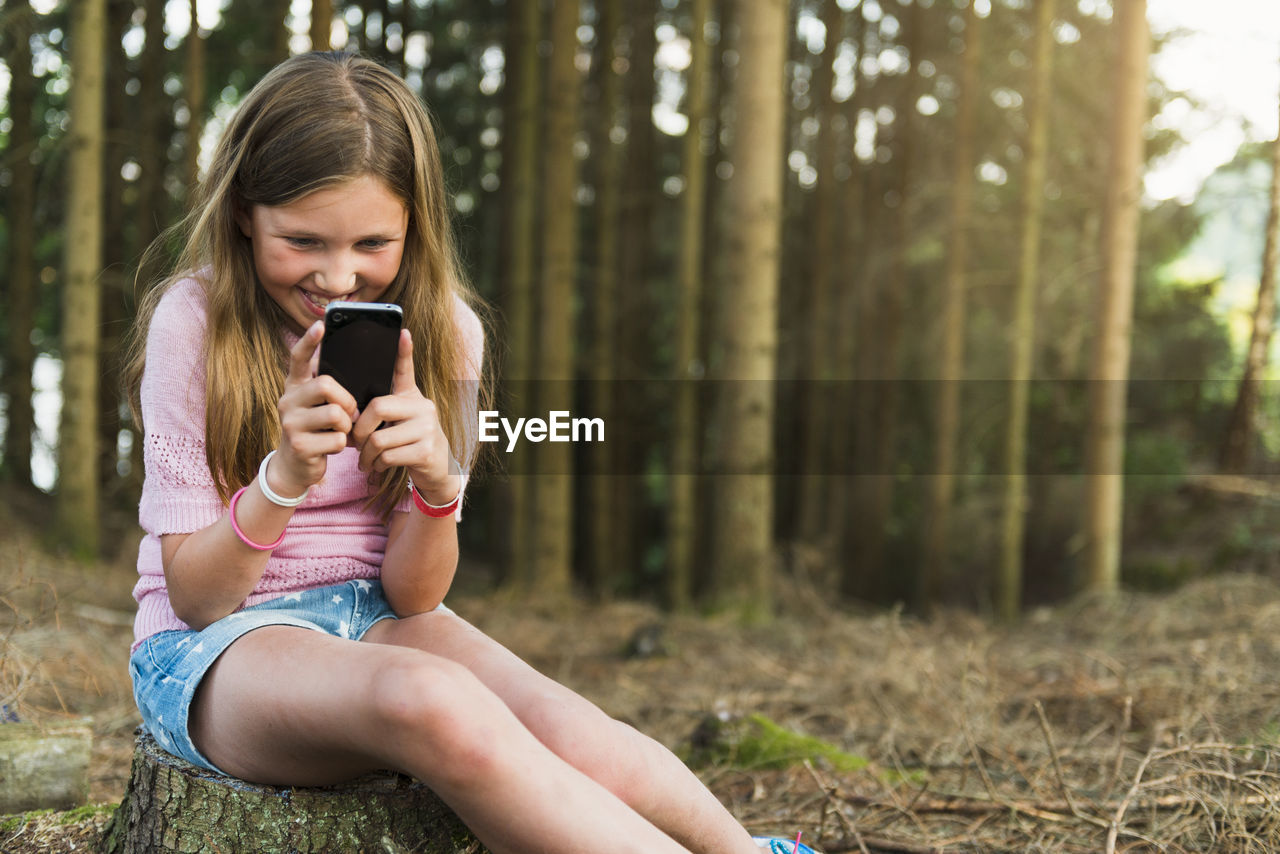 Girl with cell phone at forest