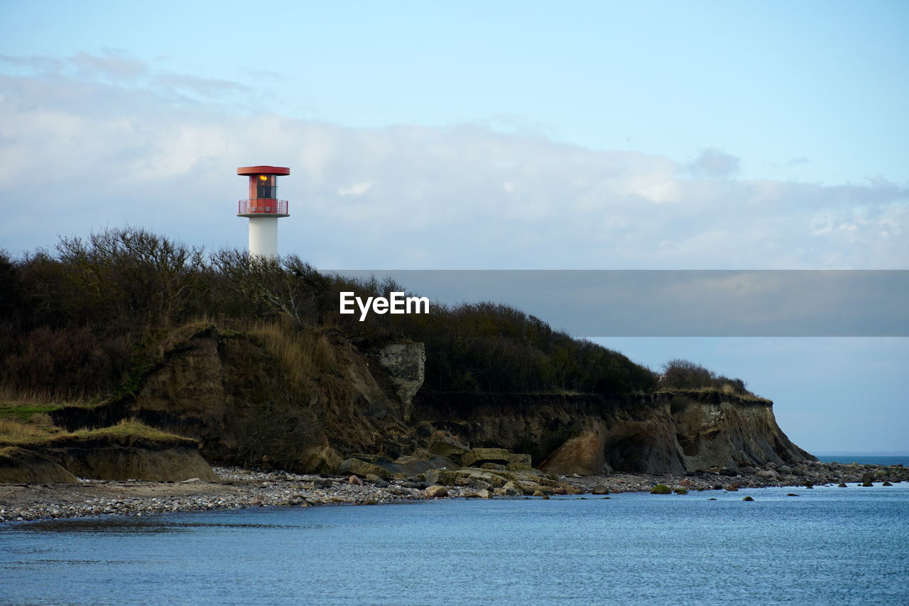 Lighthouse by sea against sky