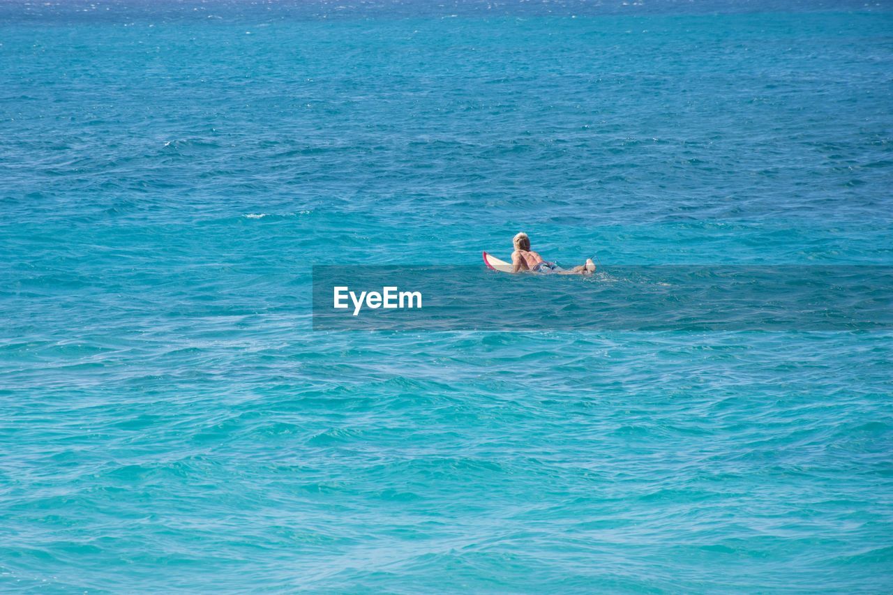 Shirtless man surfing in sea