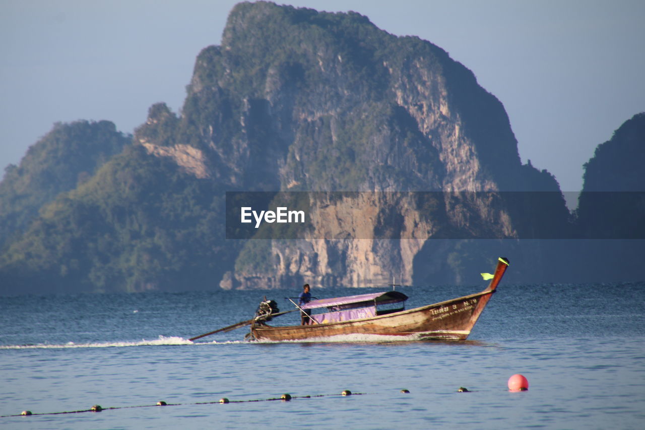 BOATS ON SEA AGAINST MOUNTAIN RANGE