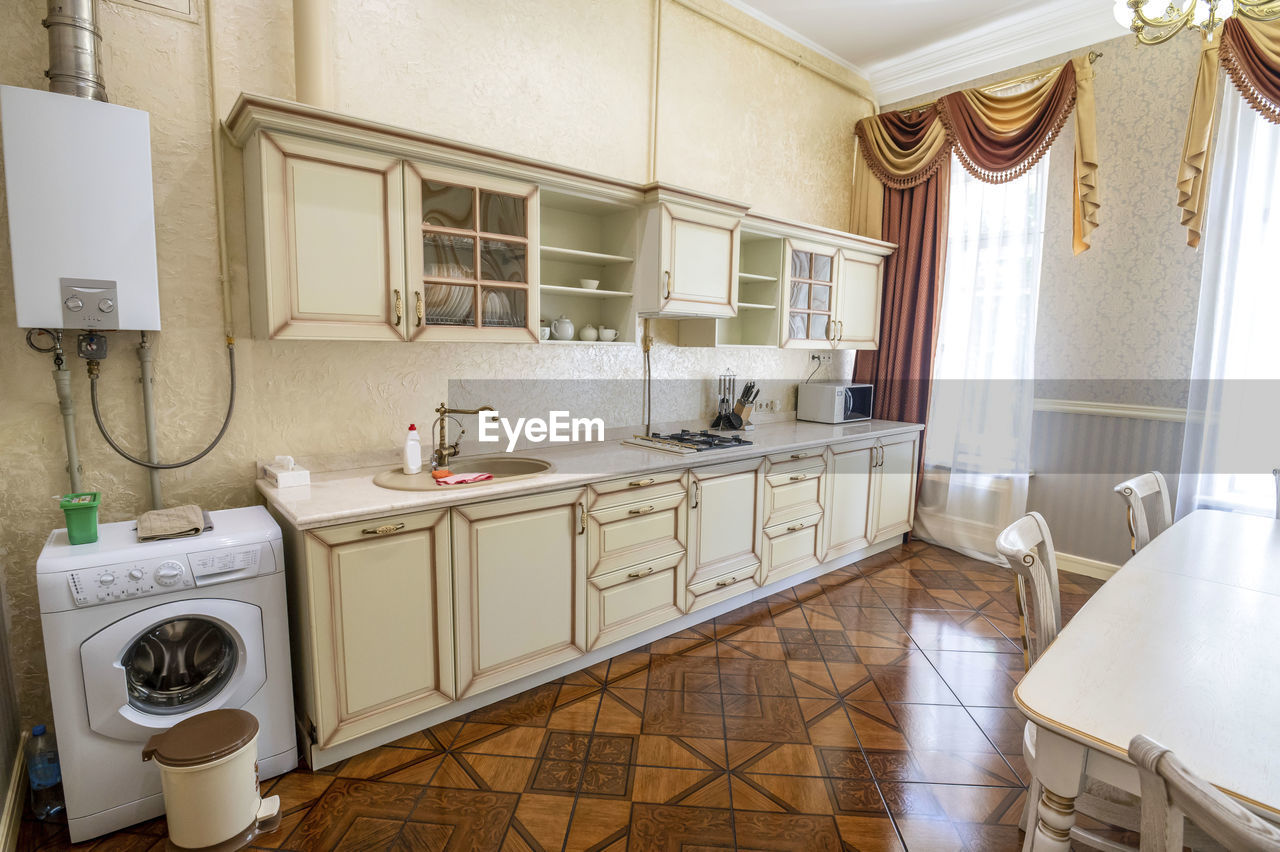 Large bright kitchen with high ceiling and linoleum flooring floor.