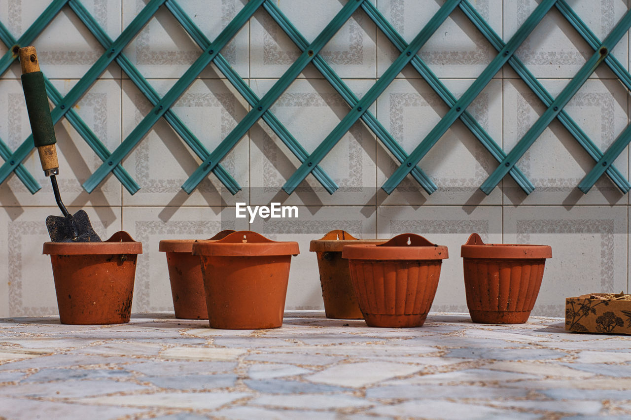 Flower pots on a marble table with a pergola on the background wall.mini shovel in a pot.