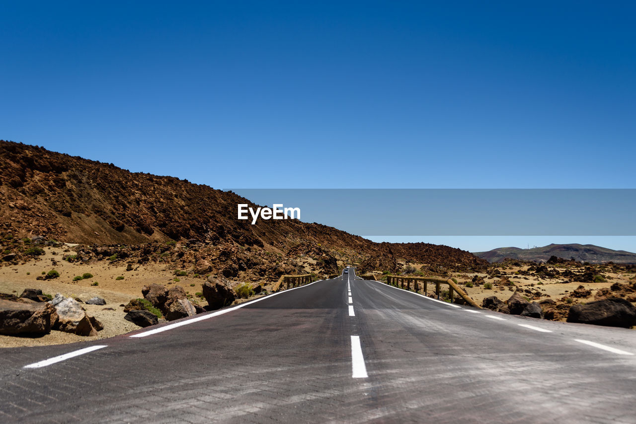 Road leading towards mountain against clear blue sky. el teide, teneriffe,  spain.