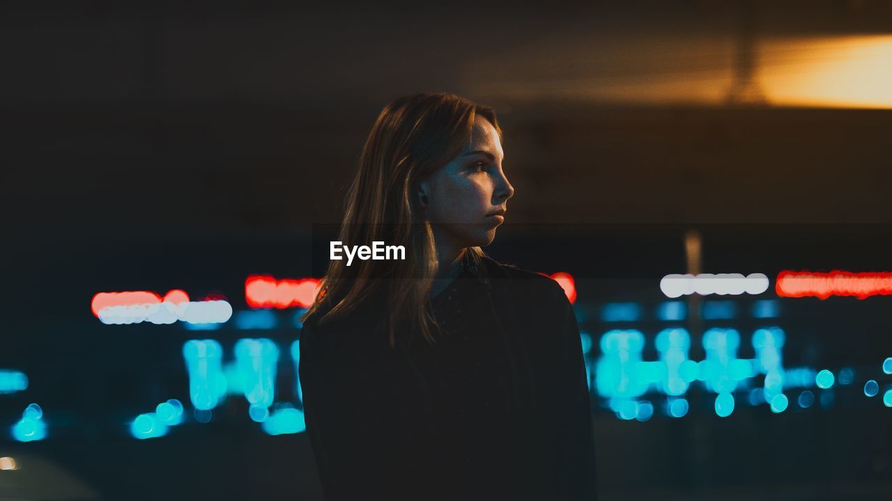 Thoughtful young woman looking away while standing at night