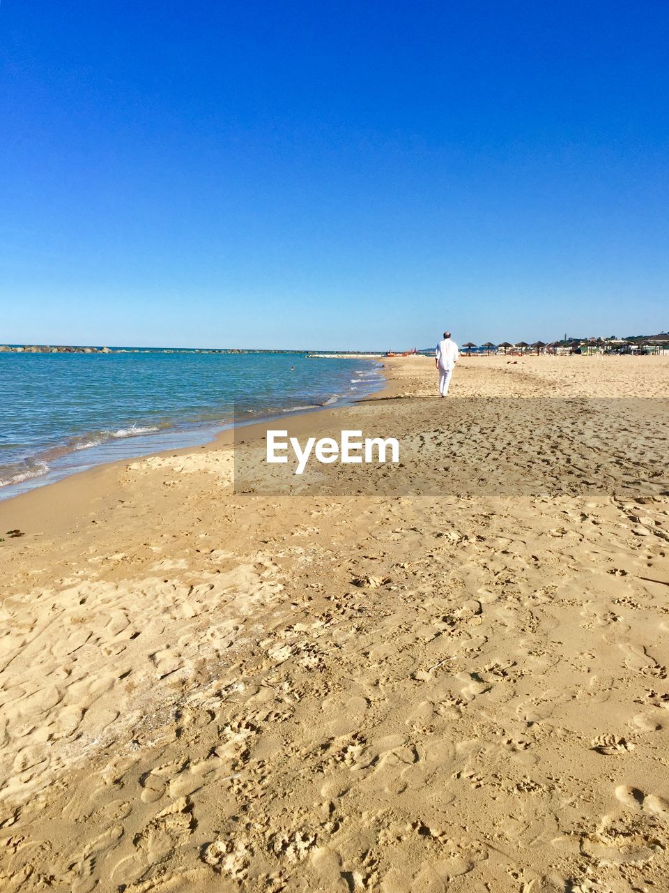 MAN AT BEACH AGAINST CLEAR SKY